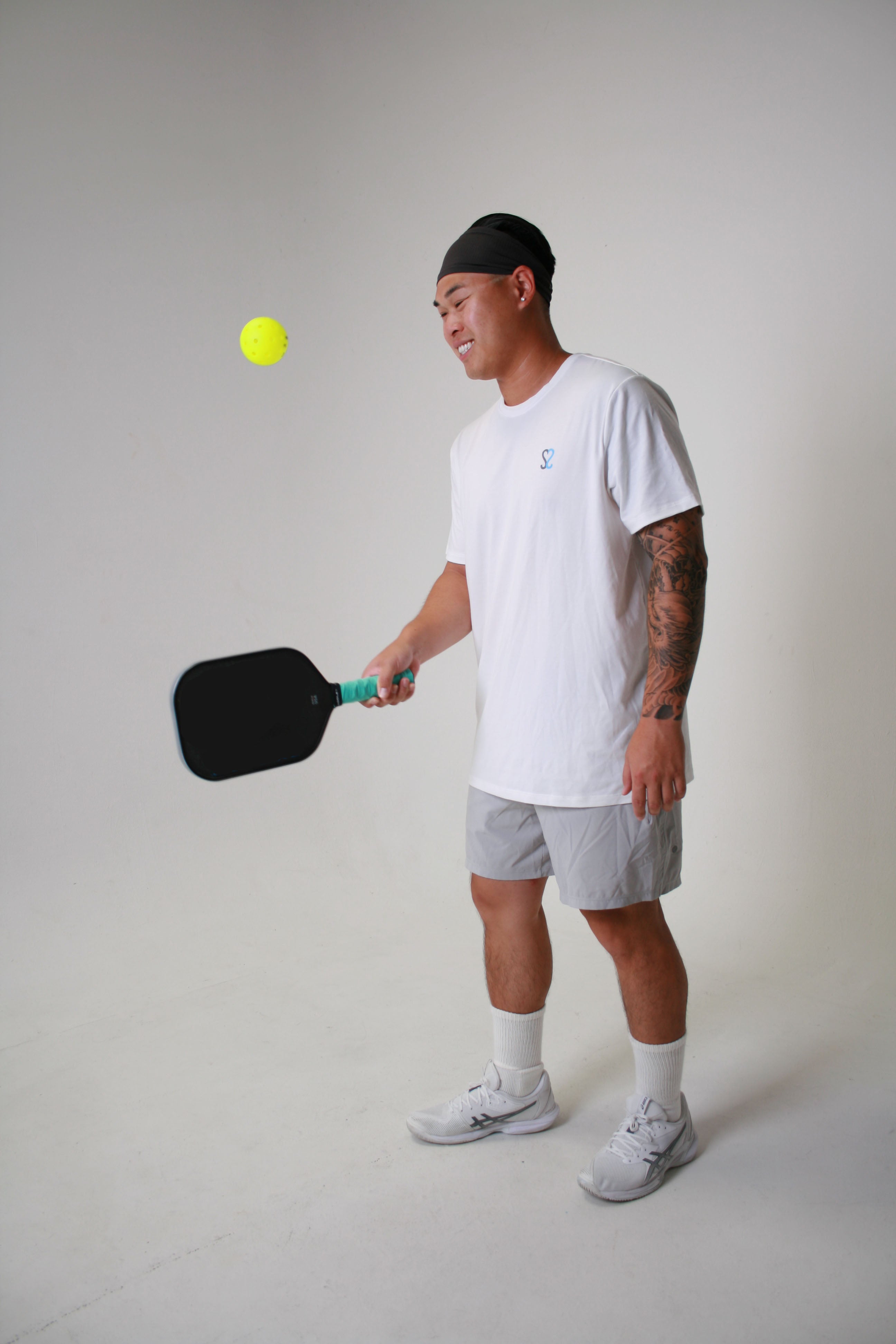 Steven hitting a ball on the side of the paddle wearing the ssnap white quick dry tee